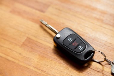 Arabanın anahtarı ahşap bir masanın üstünde. Kapıyı kilitleyip açmak için düğmeli anahtar. Araba anahtarı konsepti. Elektrik kilidi kavramı.