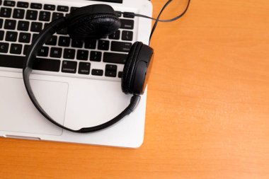 Kulaklıklı bir defter masanın üstünde. Podcast. Akıyor. Not defteri konsepti. Kulaklık konsepti.