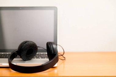 Kulaklıklı bir defter masanın üstünde. Podcast. Akıyor. Not defteri konsepti. Kulaklık konsepti.