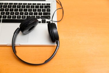 Kulaklıklı bir defter masanın üstünde. Podcast. Akıyor. Not defteri konsepti. Kulaklık konsepti.