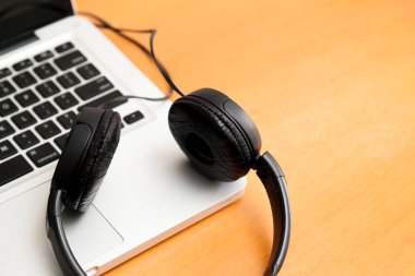 Kulaklıklı bir defter masanın üstünde. Podcast. Akıyor. Not defteri konsepti. Kulaklık konsepti.