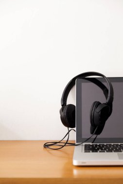 Kulaklıklı bir defter masanın üstünde. Podcast. Akıyor. Not defteri konsepti. Kulaklık konsepti.