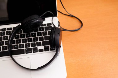 Kulaklıklı bir defter masanın üstünde. Podcast. Akıyor. Not defteri konsepti. Kulaklık konsepti.