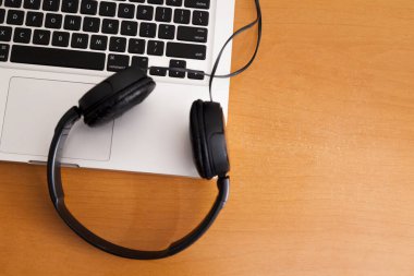 Kulaklıklı bir defter masanın üstünde. Podcast. Akıyor. Not defteri konsepti. Kulaklık konsepti.