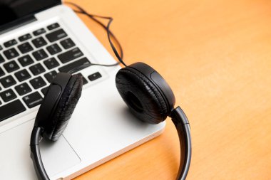 Kulaklıklı bir defter masanın üstünde. Podcast. Akıyor. Not defteri konsepti. Kulaklık konsepti.