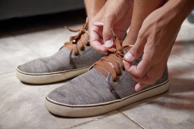 Genç Brezilyalı bir adamın tenis ayakkabısını bağlayıp mahallede yürüme alıştırması yapması. Ayakkabı konsepti. Spor konsepti.