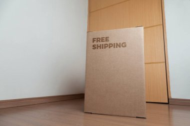 Tarafsız bir arkaplanı olan boş bir odada, yere bırakılan kutuda yazılı siparişin olduğu karton kutu. Teslimat. Ekonomi kavramı. İş konsepti. alışveriş kavramı. 