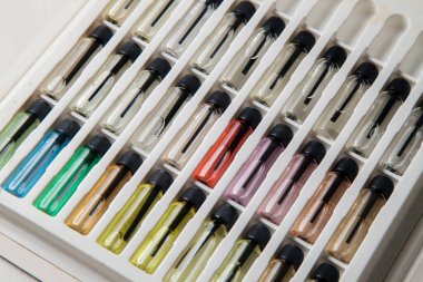 Masadaki makyaj çantasındaki farklı koku ve aromalı renkli parfüm şişeleri. Güzellik konsepti. Kadınsı bir kavram. Renkli konsept.