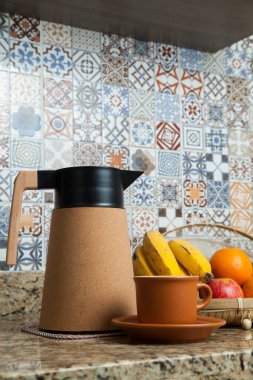 Brezilya kahvaltısı. Kahve termoslu kahvaltı masası, fincanlar ve meyveler sepette, muz, portakal, elma ve avokado. Süslü fayansları olan bir mutfakta tipik Brezilya meyveleri. Yiyecek konsepti.