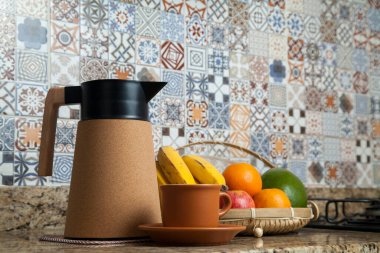 Brezilya kahvaltısı. Kahve termoslu kahvaltı masası, fincanlar ve meyveler sepette, muz, portakal, elma ve avokado. Süslü fayansları olan bir mutfakta tipik Brezilya meyveleri. Yiyecek konsepti.