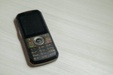 Eski hücresel cihaz merkez ofisteki masanın üstüne yerleştirilmiş, ekranı, klavyeyi ve eski elektronik cihaz teknolojisini gösteriyor. Teknoloji konsepti. iletişim konsepti