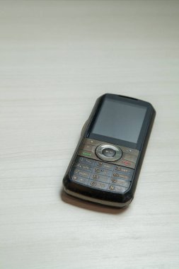 Eski hücresel cihaz merkez ofisteki masanın üstüne yerleştirilmiş, ekranı, klavyeyi ve eski elektronik cihaz teknolojisini gösteriyor. Teknoloji konsepti. iletişim konsepti