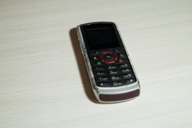 Eski hücresel cihaz merkez ofisteki masanın üstüne yerleştirilmiş, ekranı, klavyeyi ve eski elektronik cihaz teknolojisini gösteriyor. Teknoloji konsepti. iletişim konsepti