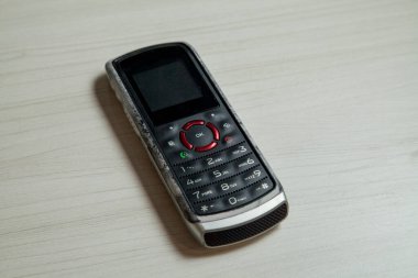 Eski hücresel cihaz merkez ofisteki masanın üstüne yerleştirilmiş, ekranı, klavyeyi ve eski elektronik cihaz teknolojisini gösteriyor. Teknoloji konsepti. iletişim konsepti