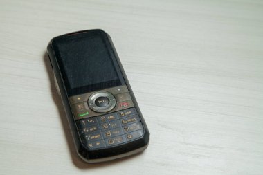 Eski hücresel cihaz merkez ofisteki masanın üstüne yerleştirilmiş, ekranı, klavyeyi ve eski elektronik cihaz teknolojisini gösteriyor. Teknoloji konsepti. iletişim konsepti