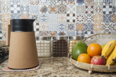 Kahve termosu, fincan ve kavanoz şeker, kahve, muz, elma, portakal ve avokado içeren Brezilya kahvaltı masası. Arka planda fayanslarla süslenmiş tipik Brezilya mutfağı. Yiyecek konsepti.