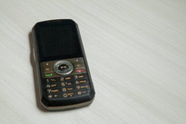 Eski hücresel cihaz merkez ofisteki masanın üstüne yerleştirilmiş, ekranı, klavyeyi ve eski elektronik cihaz teknolojisini gösteriyor. Teknoloji konsepti. iletişim konsepti