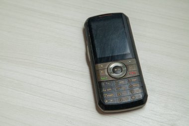 Eski hücresel cihaz merkez ofisteki masanın üstüne yerleştirilmiş, ekranı, klavyeyi ve eski elektronik cihaz teknolojisini gösteriyor. Teknoloji konsepti. iletişim konsepti