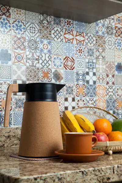 Brezilya kahvaltısı. Kahve termoslu kahvaltı masası, fincanlar ve meyveler sepette, muz, portakal, elma ve avokado. Süslü fayansları olan bir mutfakta tipik Brezilya meyveleri. Yiyecek konsepti.