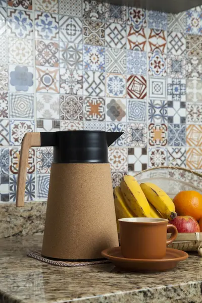 Brezilya kahvaltısı. Kahve termoslu kahvaltı masası, fincanlar ve meyveler sepette, muz, portakal, elma ve avokado. Süslü fayansları olan bir mutfakta tipik Brezilya meyveleri. Yiyecek konsepti.