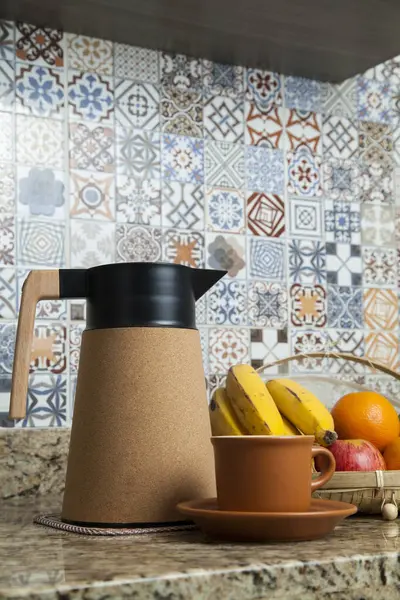 Brezilya kahvaltısı. Kahve termoslu kahvaltı masası, fincanlar ve meyveler sepette, muz, portakal, elma ve avokado. Süslü fayansları olan bir mutfakta tipik Brezilya meyveleri. Yiyecek konsepti.