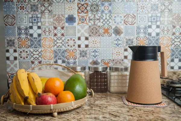 Kahve termosu, fincan ve kavanoz şeker, kahve, muz, elma, portakal ve avokado içeren Brezilya kahvaltı masası. Arka planda fayanslarla süslenmiş tipik Brezilya mutfağı. Yiyecek konsepti.