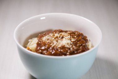 Masaya rendelenmiş peynirli bolonez soslu makarna kasesi. Yemeye hazır ve fotokopi odası var. Yemek konsepti. Makarna konsepti.
