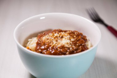 Masaya rendelenmiş peynirli bolonez soslu makarna kasesi. Yemeye hazır ve fotokopi odası var. Yemek konsepti. Makarna konsepti.