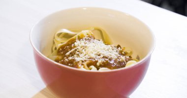 Masaya rendelenmiş peynirli bolonez soslu makarna kasesi. Yemeye hazır ve fotokopi odası var. Yemek konsepti. Makarna konsepti.