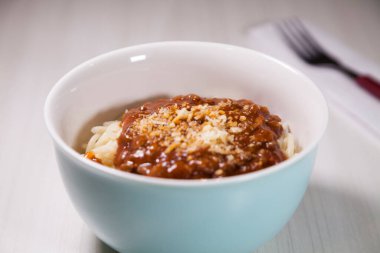 Masaya rendelenmiş peynirli bolonez soslu makarna kasesi. Yemeye hazır ve fotokopi odası var. Yemek konsepti. Makarna konsepti.