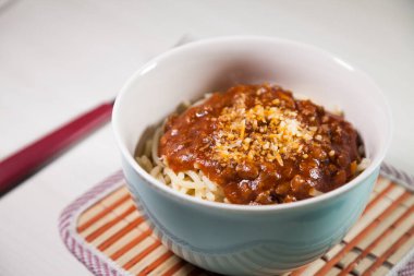 Masaya rendelenmiş peynirli bolonez soslu makarna kasesi. Yemeye hazır ve fotokopi odası var. Yemek konsepti. Makarna konsepti.