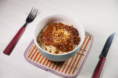 Masaya rendelenmiş peynirli bolonez soslu makarna kasesi. Yemeye hazır ve fotokopi odası var. Yemek konsepti. Makarna konsepti.