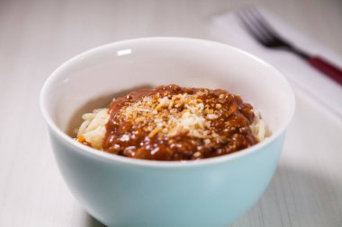 Masaya rendelenmiş peynirli bolonez soslu makarna kasesi. Yemeye hazır ve fotokopi odası var. Yemek konsepti. Makarna konsepti.