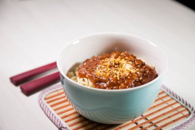 Masaya rendelenmiş peynirli bolonez soslu makarna kasesi. Yemeye hazır ve fotokopi odası var. Yemek konsepti. Makarna konsepti.