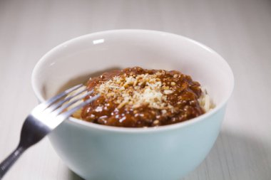 Masaya rendelenmiş peynirli bolonez soslu makarna kasesi. Yemeye hazır ve fotokopi odası var. Yemek konsepti. Makarna konsepti.