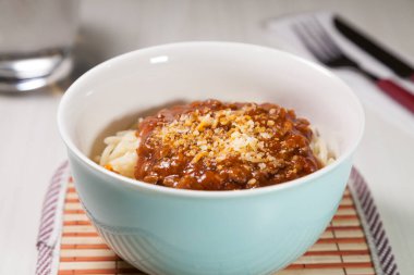 Masaya rendelenmiş peynirli bolonez soslu makarna kasesi. Yemeye hazır ve fotokopi odası var. Yemek konsepti. Makarna konsepti.