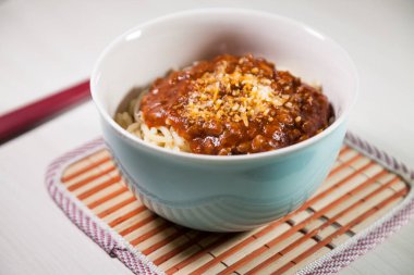 Masaya rendelenmiş peynirli bolonez soslu makarna kasesi. Yemeye hazır ve fotokopi odası var. Yemek konsepti. Makarna konsepti.