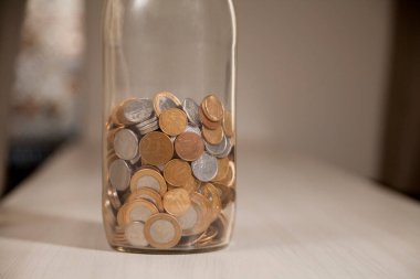 Gerçek para, Brezilya 'dan gelen para. Masanın üzerine para istiflenmiş, üstünde de siyah arka planlı kasvetli ve karanlık iklimli bir bozuk para var. Brezilya ekonomisi, yatırımlar, gelir. Brezilya para birimi 