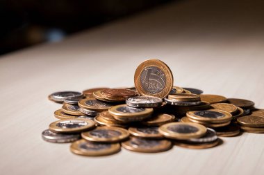 Gerçek para, Brezilya 'dan gelen para. Masanın üzerine para istiflenmiş, üstünde de siyah arka planlı kasvetli ve karanlık iklimli bir bozuk para var. Brezilya ekonomisi, yatırımlar, gelir. Brezilya para birimi 