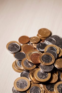 Real currency, money from Brazil. Coins stacked on the table, with a coin at the top with a gloomy and dark climate with a black background. Brazilian economy, investments, income. Brazilian currency 
