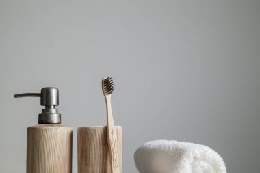 Bambu diş fırçaları, diş macunu, gri masada beyaz havlu. Banyo, ekolojik diş bakım ürünleri ve sağlıklı yaşam tarzı konsepti. Ağız temizliği kavramı