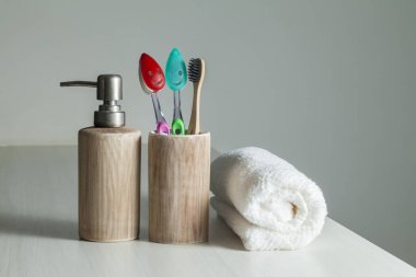 Bambu diş fırçaları, diş macunu, gri masada beyaz havlu. Banyo, ekolojik diş bakım ürünleri ve sağlıklı yaşam tarzı konsepti. Ağız temizliği kavramı