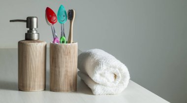 Bambu diş fırçaları, diş macunu, gri masada beyaz havlu. Banyo, ekolojik diş bakım ürünleri ve sağlıklı yaşam tarzı konsepti. Ağız temizliği kavramı