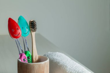 Bambu diş fırçaları, diş macunu, gri masada beyaz havlu. Banyo, ekolojik diş bakım ürünleri ve sağlıklı yaşam tarzı konsepti. Ağız temizliği kavramı