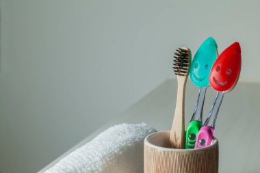 Bambu diş fırçaları, diş macunu, gri masada beyaz havlu. Banyo, ekolojik diş bakım ürünleri ve sağlıklı yaşam tarzı konsepti. Ağız temizliği kavramı