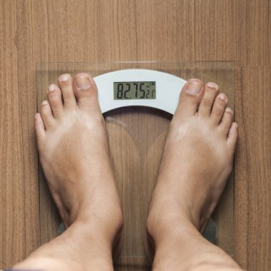 Tahta zeminde ağırlık kontrolü için dijital ölçekte duran çıplak ayaklı erkek. Birinci şahıs görüşü. Zayıflatıcı konsept. Diyet konsepti. Sağlık kavramı.