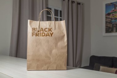 Karton poşet, arka planda özel yazı ve mutfak olan masa kahverengi kağıt ambalajına Kara Cuma yazılıydı. Kara Cuma konsepti. Ürün konsepti. Paketleme konsepti. Boşluğu kopyala