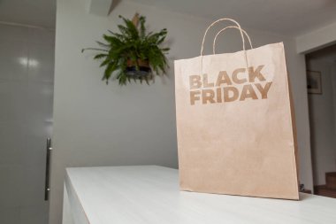 Karton poşet, arka planda özel yazı ve mutfak olan masa kahverengi kağıt ambalajına Kara Cuma yazılıydı. Kara Cuma konsepti. Ürün konsepti. Paketleme konsepti. Boşluğu kopyala