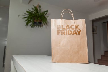 Karton poşet, arka planda özel yazı ve mutfak olan masa kahverengi kağıt ambalajına Kara Cuma yazılıydı. Kara Cuma konsepti. Ürün konsepti. Paketleme konsepti. Boşluğu kopyala