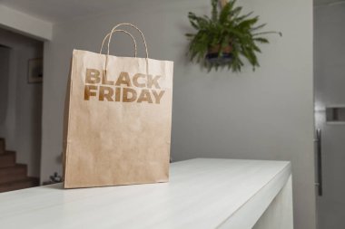 Karton poşet, arka planda özel yazı ve mutfak olan masa kahverengi kağıt ambalajına Kara Cuma yazılıydı. Kara Cuma konsepti. Ürün konsepti. Paketleme konsepti. Boşluğu kopyala